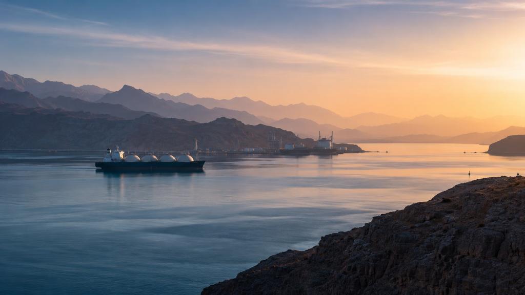 Aube calme sur le détroit d’Ormuz, mer lisse, silhouette de méthanier, montagnes désertiques et lumière douce, illustration éditoriale générée par IA.